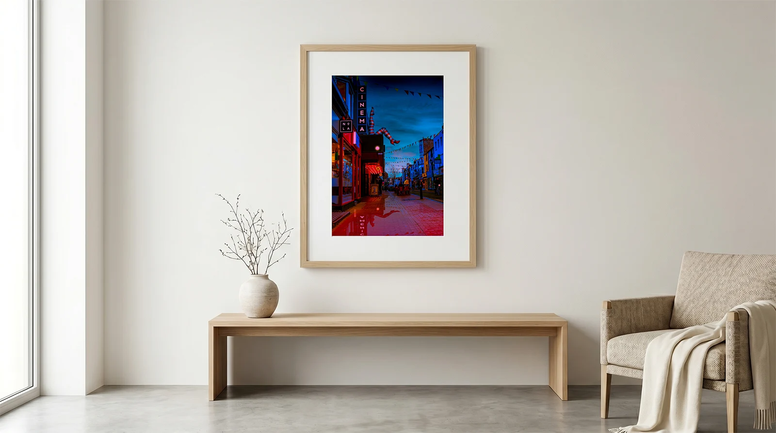 komedia brighton framed in living room brian roe Large wood-framed fine art print of Brighton Komedia cinema at twilight hanging on a white living room wall above a modern oak bench.