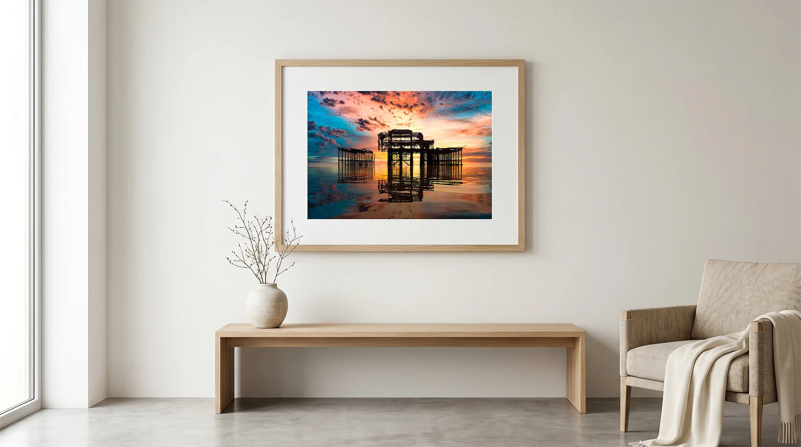 Brian Roe fine art print of the West Pier Brighton hanging over a light wood bench in a modern Scandinavian living room.