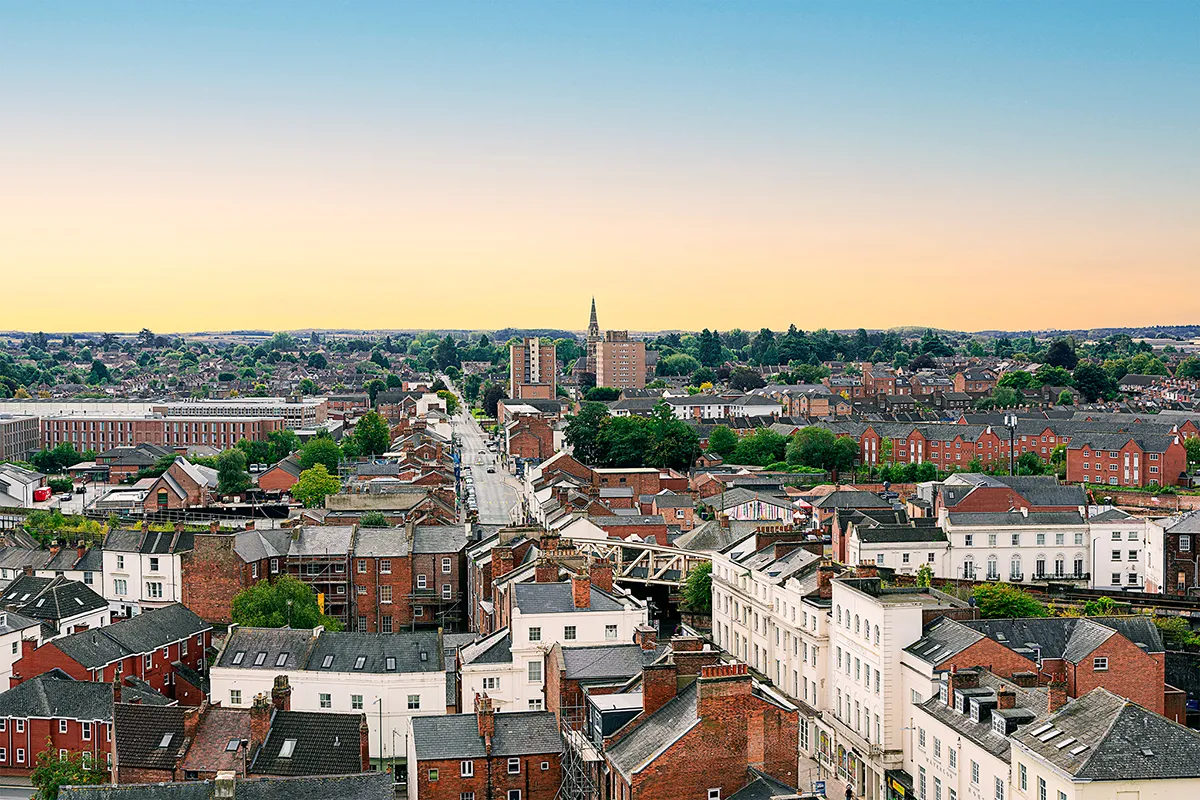 A high-angle view looking over the brick rooftops, urban street layout, and residential chimneys of South Leamington Spa at sunrise.