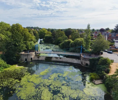 Aerial view of the blue iron Mill Bridge and stepped weir on the River Leam in Royal